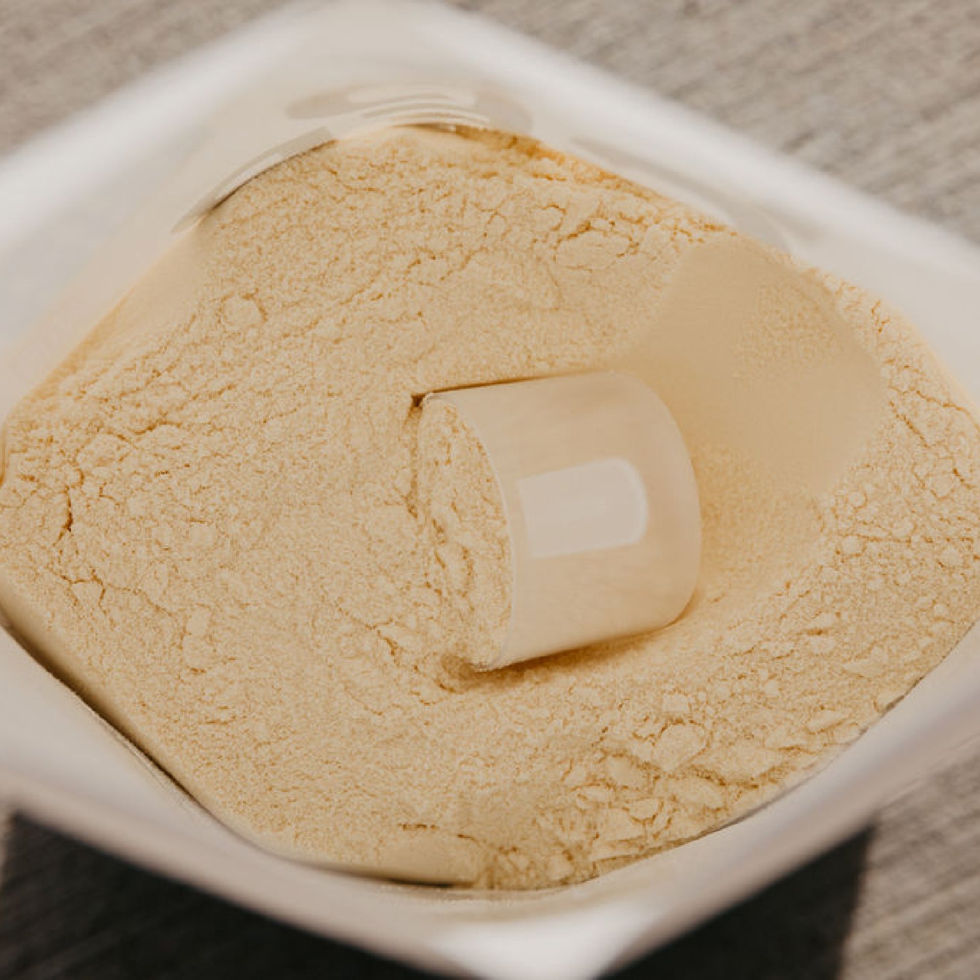 Close up of the inside of a bag of white protein powder with a scoop